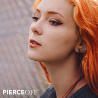 beautiful red-headed woman with lip ring in front of chain fence