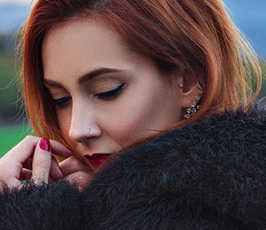 fashionable woman wearing fluffly coat with nose, tragus piercings and ear piercings
