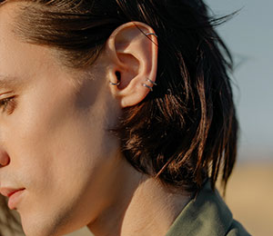 fashionable man with tragus ring piercing and multiple earlobe piercings