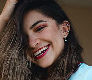 laughing girl with multiple ear piercings, tragus piercing jewellery, helix piercings