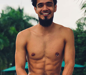 smiling shirtless young man with nipple ring jewellery in nipple piercing