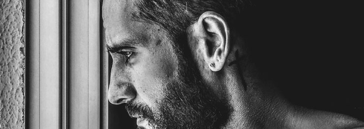 Guy with ear piercing staring out a window